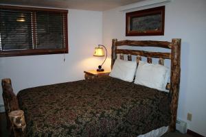a bedroom with a bed and a lamp on a table at Timber Creek Chalets- 14 chalet in Estes Park