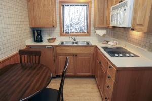 uma cozinha com armários de madeira, um lavatório e uma mesa em Sunnyside Knoll- 8 cabin em Estes Park