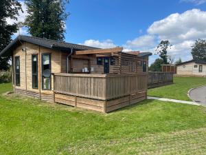 a wooden cabin with a deck on the grass at Glasshouse lodge 