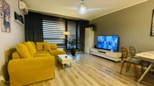 sala de estar con sofá amarillo y TV de pantalla plana en Millennium La Tour, en Varsovia