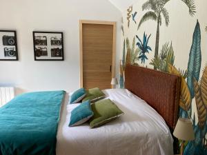 a bedroom with a bed with blue and green pillows at LE CLOS DAUPHINAIS Chez Laurette in Quévert