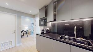 a kitchen with white cabinets and a black counter top at Time Place Tower - Vacationer in Dubai
