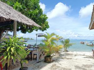 a beach with a table and chairs and the ocean at Koh Mook Sea View Bungalow in Koh Mook