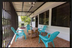 a porch with blue chairs and a wooden table at CASA KENJY in Quepos
