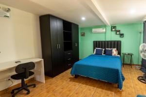 1 dormitorio con cama azul, escritorio y silla en CASA KENJY, en Quepos