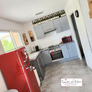 a kitchen with a red refrigerator in a room at A 2 pas des vignes, hebergements et Spa, maison numéro 12 à Châteauneuf du Pape in Châteauneuf-du-Pape