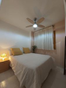 a bedroom with a white bed with a ceiling fan at Apartamento en el centro de zaragoza "EL RUBÍ DEL PILAR" in Zaragoza