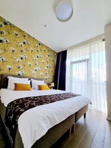 - une chambre avec un grand lit et un mur jaune dans l'établissement ALEGRE apartment, à Druskininkai