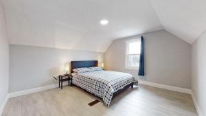 a white bedroom with a bed and a window at Newly Renovated 3 Bedroom in Hamilton