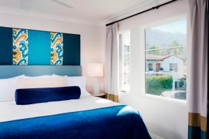 a bedroom with a blue and white bed and a window at Triada Palm Springs, Autograph Collection in Palm Springs