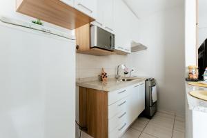 a small kitchen with a sink and a refrigerator at Super bem localizado, no centro, com varanda! in Poços de Caldas