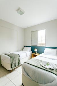 a bedroom with two beds and a window at Super bem localizado, no centro, com varanda! in Poços de Caldas