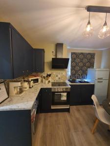 a kitchen with black cabinets and a white refrigerator at Stylish Kent Gem - Free WiFi in Kent