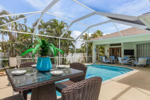 eine Terrasse mit einem Tisch und Stühlen neben einem Pool in der Unterkunft Newly Renovated Villa with Heated Pool! - Villa Taina - Roelens Vacations in Cape Coral
