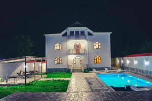 a white house with a swimming pool at night at Gabala Regnum Family Villa in Gabala