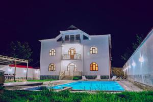 a large white house with a swimming pool at night at Gabala Regnum Family Villa in Gabala
