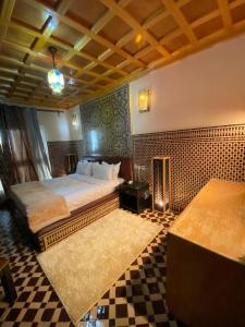 a bedroom with a bed and a checkered floor at Hôtel-Café-Restaurant Pyramides, in Taza