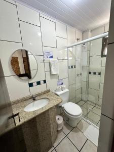 bagno con servizi igienici, lavandino e specchio di Hotel D'Luz a Itapema
