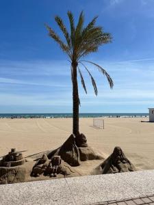 una escultura de arena de una palmera en una playa en Apartamento 1ª Línea de Playa - Con Piscina y Parking, en Gandía
