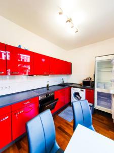 una cocina con armarios rojos y sillas azules en VIP Wohnung Heidelberg, en Heidelberg