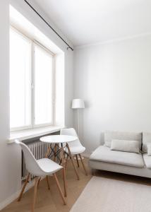 a white living room with a couch and a table and chairs at Cozy apartment close to Helsinki Cathedral in Helsinki