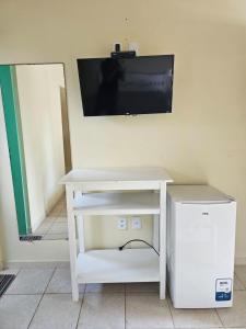 einen weißen Tisch mit einem TV an der Wand in der Unterkunft Suítes Maresias in São Sebastião