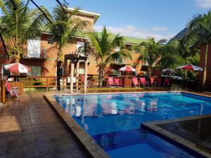 a large swimming pool with palm trees and a building at Residencial dos Portugas in Boracéia