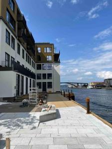 un edificio junto a un cuerpo de agua con un banco en Sentrums-nær leilighet med sjøutsikt, en Bergen