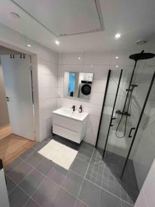 a white bathroom with a sink and a shower at Sentrums-nær leilighet med sjøutsikt in Bergen