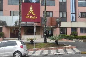 a car parked in front of a large building at Apart Hotel 48 in Mogi das Cruzes