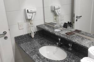 a bathroom counter with a sink and a phone at Apart Hotel 48 in Mogi das Cruzes
