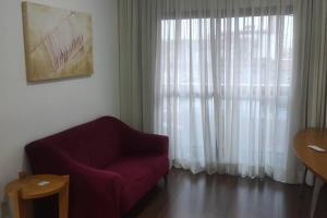 a living room with a purple chair and a window at Apart Hotel 48 in Mogi das Cruzes