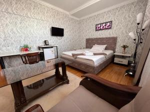 1 dormitorio con cama, escritorio y sofá en MASSAGET HOTEL, en Nukus