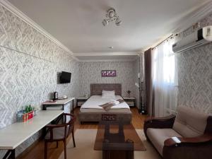 um quarto com uma cama, uma secretária e um sofá em MASSAGET HOTEL em Nukus