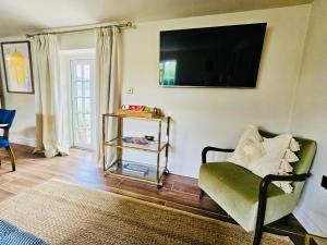 a living room with a couch and a television on the wall at Cotswolds Cottage 5min from Soho Farmhouse in Chipping Norton