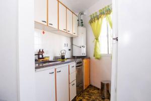 サンタ・テレシータにあるLa casita de la Costaの白いキャビネット、シンク、窓付きのキッチン