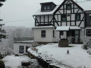 a black and white house covered in snow at Ferienwohnung Schäfer in Waldbreitbach