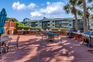 a patio with tables and chairs and a grill and a building at Fabulous Park Shore Condo in Naples