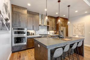 a kitchen with wooden cabinets and a large island with bar stools at On Top of the Mountains - Full Townhome in Keetley
