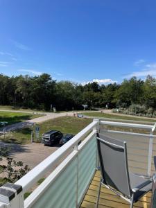 eine Terrasse mit einem Stuhl und einem Auto auf einem Parkplatz in der Unterkunft Apartment Strandglück in Dierhagen + 1 Foto