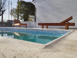 una piscina con 2 bancos junto a un edificio en Cabaña Las Seis Maravillas en Nono