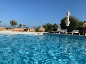 a large swimming pool with an umbrella and a chair at "La Janca" in San Pietro in Bevagna