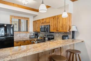 a kitchen with wooden cabinets and a black refrigerator at Snow Flower 206 in Steamboat Springs