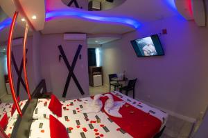 a bedroom with a bed with red and white sheets at Manhattan Motel (Adult Only) in Porto Alegre