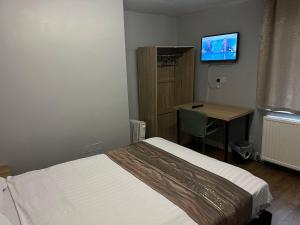 a bedroom with a bed and a desk and a television at Assheton Hotel in Middleton