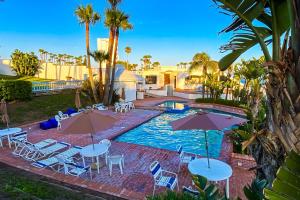 a swimming pool with tables and umbrellas in front of a house at Club Marena Condo 501 in Rosarito