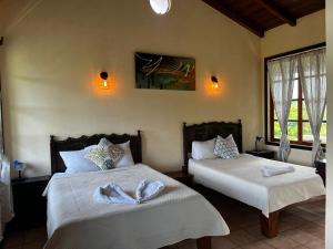 a bedroom with two beds with white sheets at Hotel La Colina in Manuel Antonio