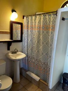 a bathroom with a shower curtain and a sink at Hotel La Colina in Manuel Antonio