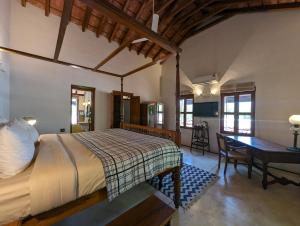 een slaapkamer met een bed en een bureau in een kamer bij Thanga House by LuxUnlock Private Villas in Tarangambādi