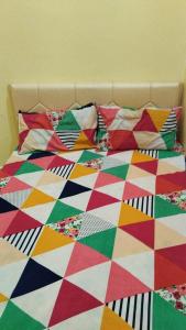 a bed with a colorful comforter and pillows on it at Shubham guest house in Muzaffarpur